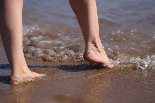 istock Barefoot female feet on surf on sea line 1321860323