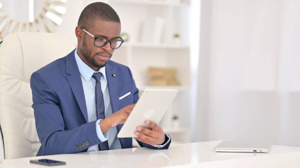 istock Professional Young African Businessman using Tablet in Office 1321867614