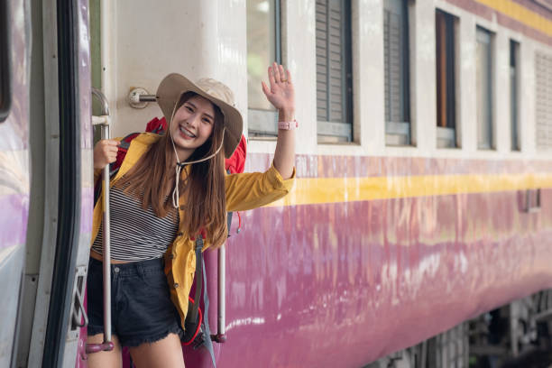 istock Young beautiful female traveler with backpack smiling and waving hand while getting on the train and ready for her summer trip. 1321867776