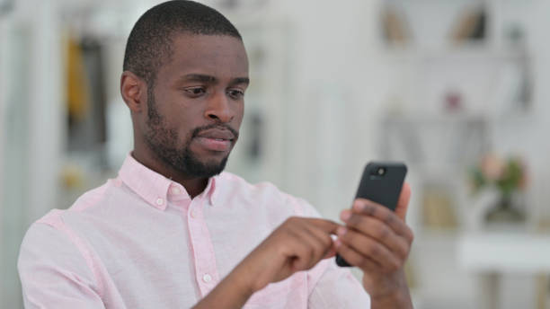 istock Portrait of Serious African Man using Smartphone 1321867786