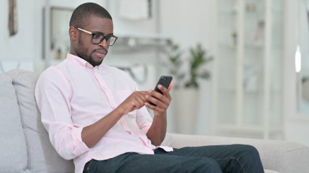 istock Relaxed African Man using Smartphone at Home 1321868791