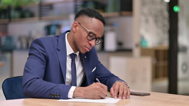 istock Serious Young African Businessman doing Paperwork in Office 1321868937