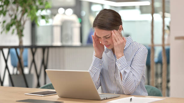 istock Stressed Woman with Laptop having Headache in Office 1321870504