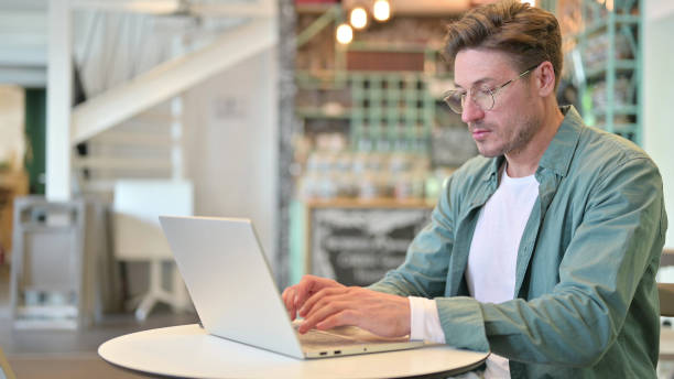 istock Middle Aged Man Working on Laptop in Cafe 1321870590