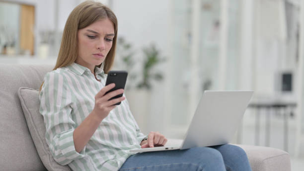 istock Young Woman using Smartphone and Laptop at Home 1321871585
