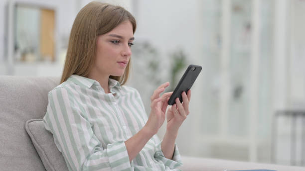 istock Serious Young Woman using Smartphone at Home 1321871642