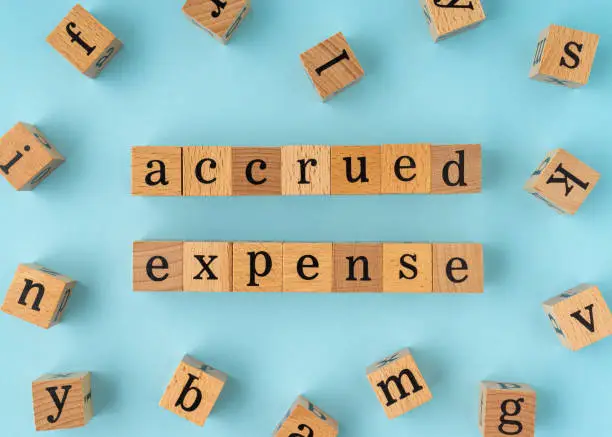 Photo of Accrued Expense word on wooden block. Flat lay view on blue background.
