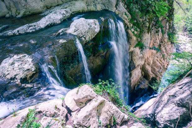 A scenic stream of a waterfall falling among a rocky gorge. Agur river in Khosta microdistrict, Russia. Travelling, hiking and recreation in the mountains.