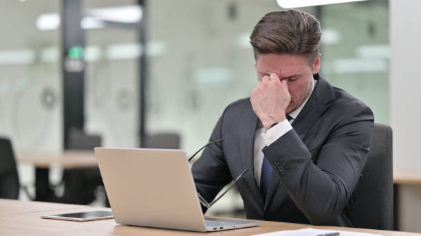 istock Stressed Middle Aged Businessman with Laptop having Headache in Office 1321876318