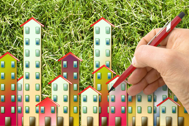 istock Cities and green spaces - concept with architect drawing a residential district over a green mowed lawn background 1321879520