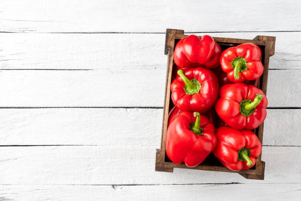 tiro em cima de pimentão vermelho na caixa em mesa de madeira branca com espaço de cópia. páprica doce - pepper bell pepper growth ripe - fotografias e filmes do acervo