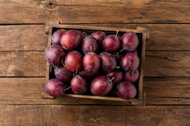 Overhead shot of plums in box on rustic wooden table