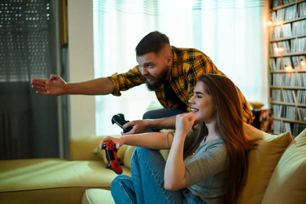 istock Young beautiful couple playing video games while relaxing at home 1321884069