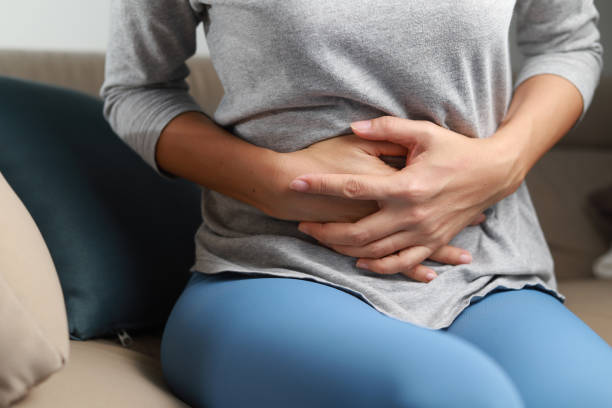 Female stomachache or menstruation pain sitting on a sofa. stock photo