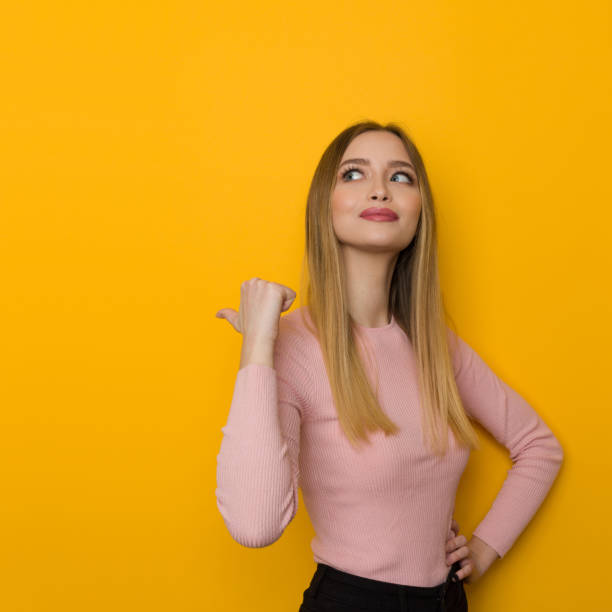 istock Confident Young Woman Is Pointing With Thumb Behind Herself. 1321897885