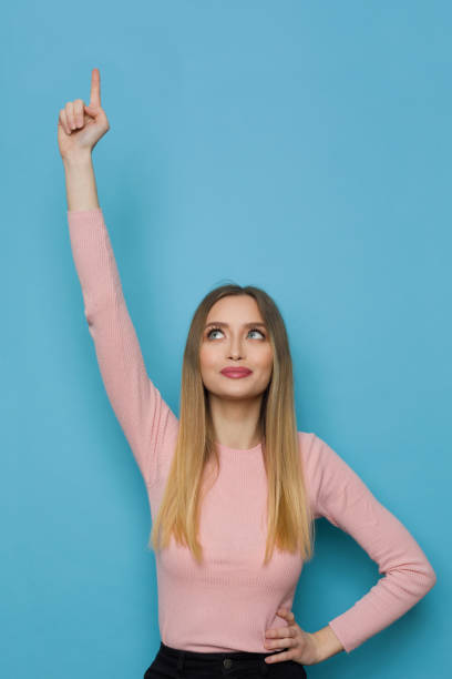 istock Cheerful Young Woman Is Pointing Up And Looking 1321897889