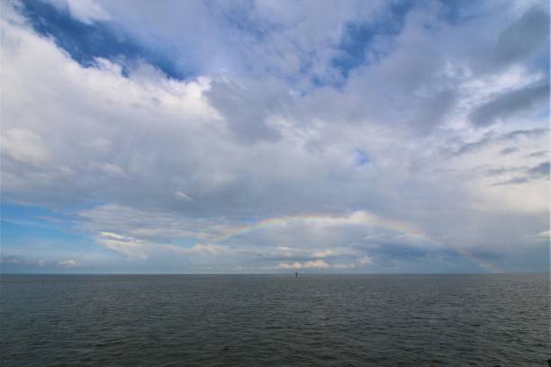 istock Rainbow above the north sea against a blue sky with clouds 1321903090