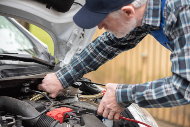 Car mechanic using car battery jumper cable stock photo