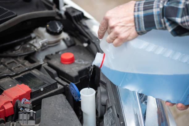 istock Hands of mechanic pouring windshield washer fluid in a car 1321903495