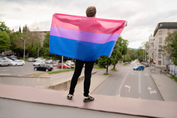 ein mann hält die lesbische flagge, um seine unterstützung zu zeigen - bi sexual stock-fotos und bilder
