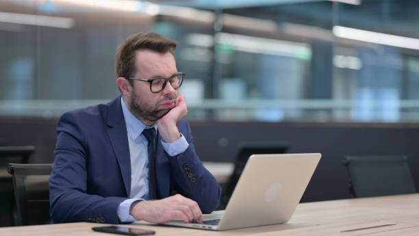 istock Middle Aged Businessman with Laptop Taking Nap at Work 1321908490