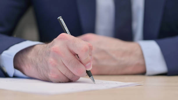 istock Hands Close up of Middle Aged Businessman Writing on Paper 1321908498