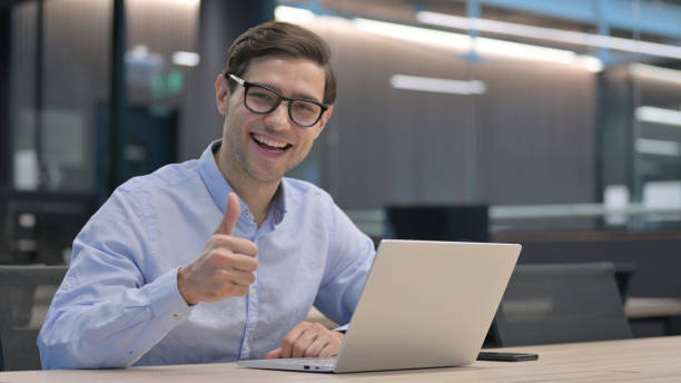 istock Thumbs Up by Young Man with Laptop at Work 1321908629