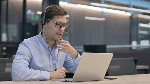 istock Young Man with Headset Making Video Call on Laptop 1321908813