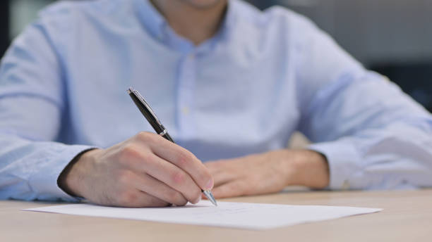 istock Hands Close up of Young Man Writing on Paper 1321908822