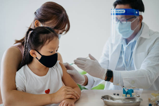 Young girl getting a vaccine injection on her arm Image of a young asian girl getting a vaccine injection on her arm from a healthcare worker. Woman accompanying her daughter to get a vaccine injection at medical clinic. herd immunity photos stock pictures, royalty-free photos & images