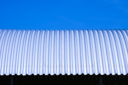 Front view of curved steel roof against blue clear sky background