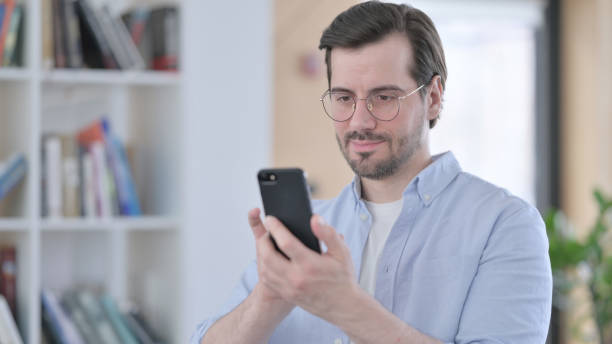 istock Portrait of Man in Glasses using Smartphone 1321918146