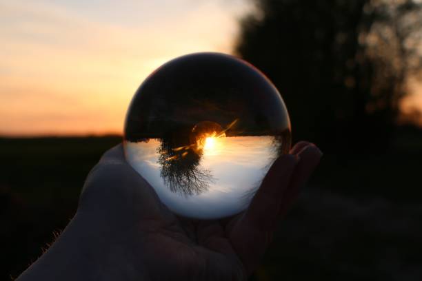 istock a sunset in a beautiful landscape view through a glass ball held by one hand 1321918757