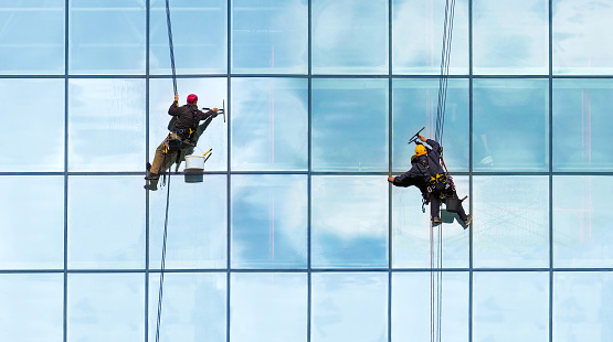 Grupo de trabajadores de limpieza de ventanas de servicio en edificio de gran altura. Trabajadores limpiando muro cortina de vidrio. Concepto especial de trabajo, vista panorámica photo