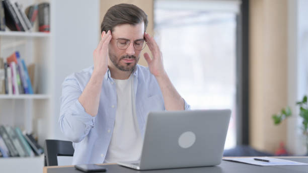 istock Tired Man in Glasses with Laptop having Headache 1321921658
