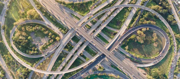 Aerial view of road interchange or highway intersection with busy urban traffic speeding on the road. Junction network of transportation taken by drone.