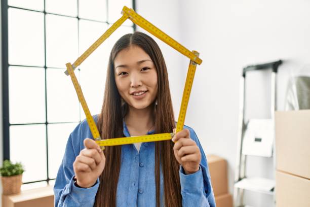 新しい家に立って幸せなホールディングハウスプロジェクトを笑顔の若い中国の女の子 - natural form ストックフォトと画像