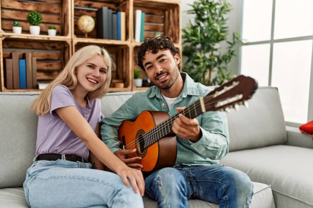 istock Man playing spanish guitar to his girlfriend sitting on the sofa at home 1321932035