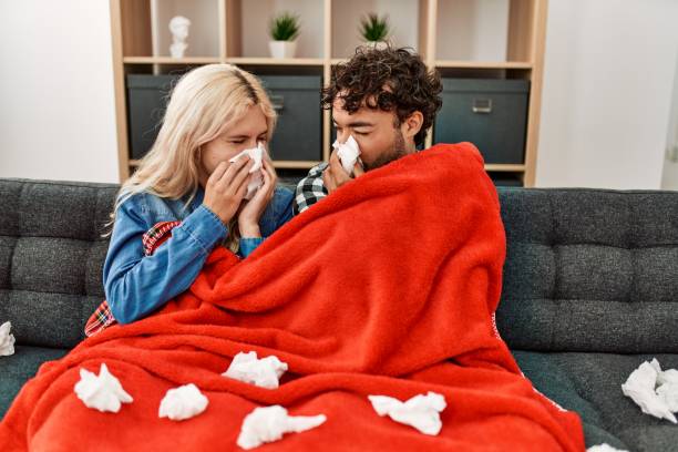 istock Young ill couple using napkin sititng on the sofa at home. 1321932072