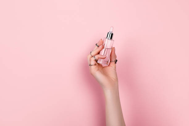 istock Female hand holding hyaluronic bottle from torn paper 1321933515