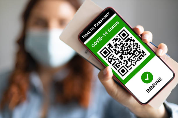 jovem usando uma máscara facial segurando passaporte, ticket pass e smartphone com aplicativo de passaporte de saúde digital para viajar durante a pandemia covid-19. - immune cell - fotografias e filmes do acervo