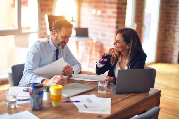 istock Two middle age business workers smiling happy and confident. Working together with smile on face using laptop at the office 1321934906