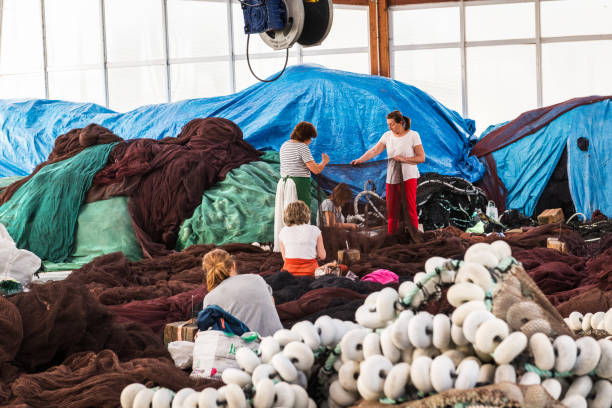 Group of Galician net-menders repairing fish nets at Portonovo fisherman wharf, Galicia, Spain.