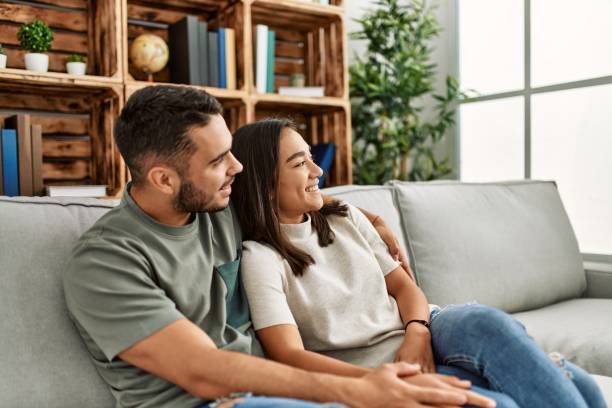 istock Young latin couple sitting on the sofa hugging at home. 1321937248