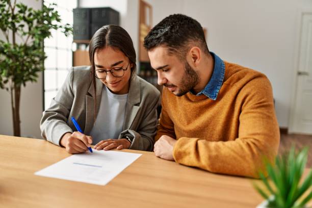 Couple smiling happy signing contract at the office. Couple smiling happy reading document at the office. iberian ethnicity stock pictures, royalty-free photos & images