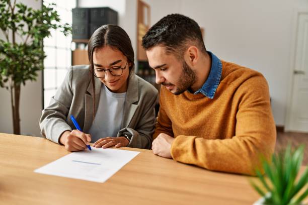 couple smiling happy signing contract at the office. - women men signing business imagens e fotografias de stock