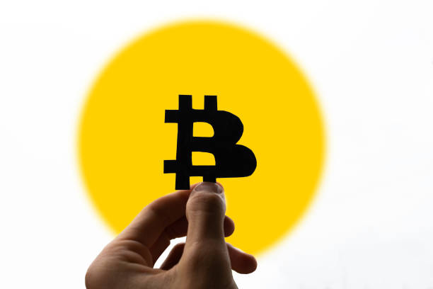 istock black bitcoin logo in hand on yellow circle background. cryptocurrency sphere concept 1321940060