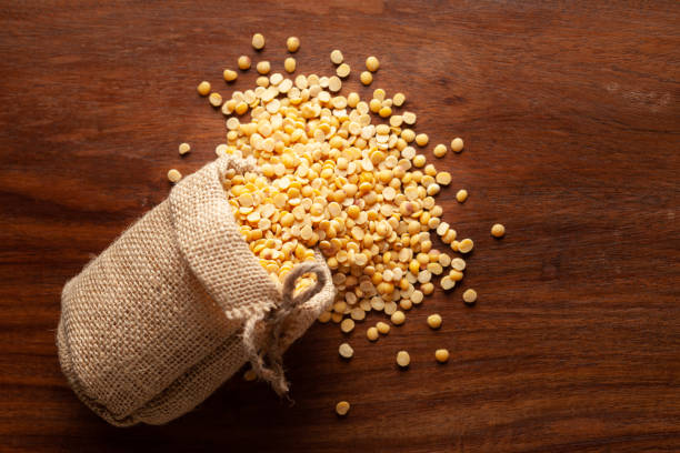 primer plano de arhar dal orgánico (cajanus cajan) o dal amarillo partido derramado de una bolsa de yute tendido sobre fondo marrón de madera. - pigeon pea” fotografías e imágenes de stock