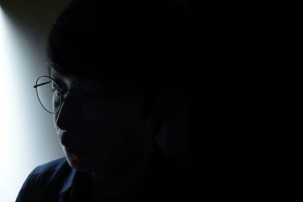 istock A Asian man wear glasses and thinking in dark. 1321946096