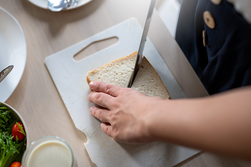 Close-up shot of a young mother making healthy sandwiches for breakfast in the kitchen.